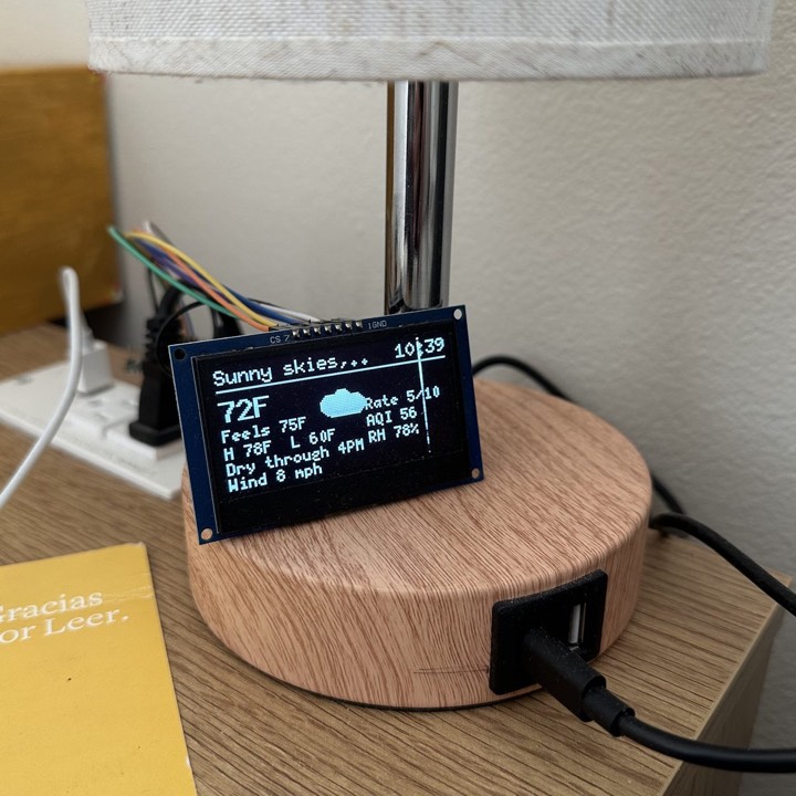 The bedside display on its lamp base, showing the weather: 72 degrees, sunny, with the day's high and low, air quality, and wind.